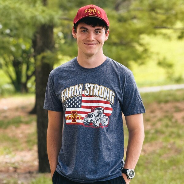 A student wearing College House I-State Navy Farmstrong Iowa ISF26 Short Sleeve T-Shirt and hat